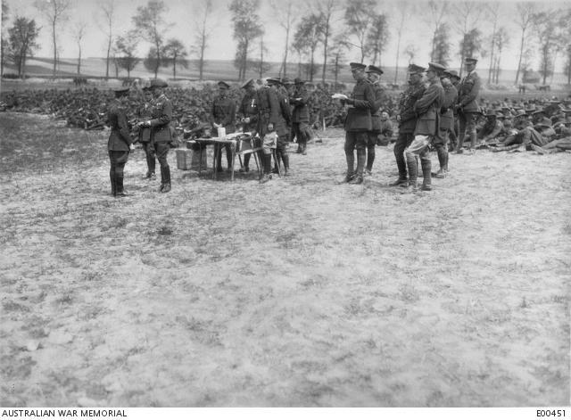 An image of a graoupd of soldiers and one is presenting an award to to a brave Officer